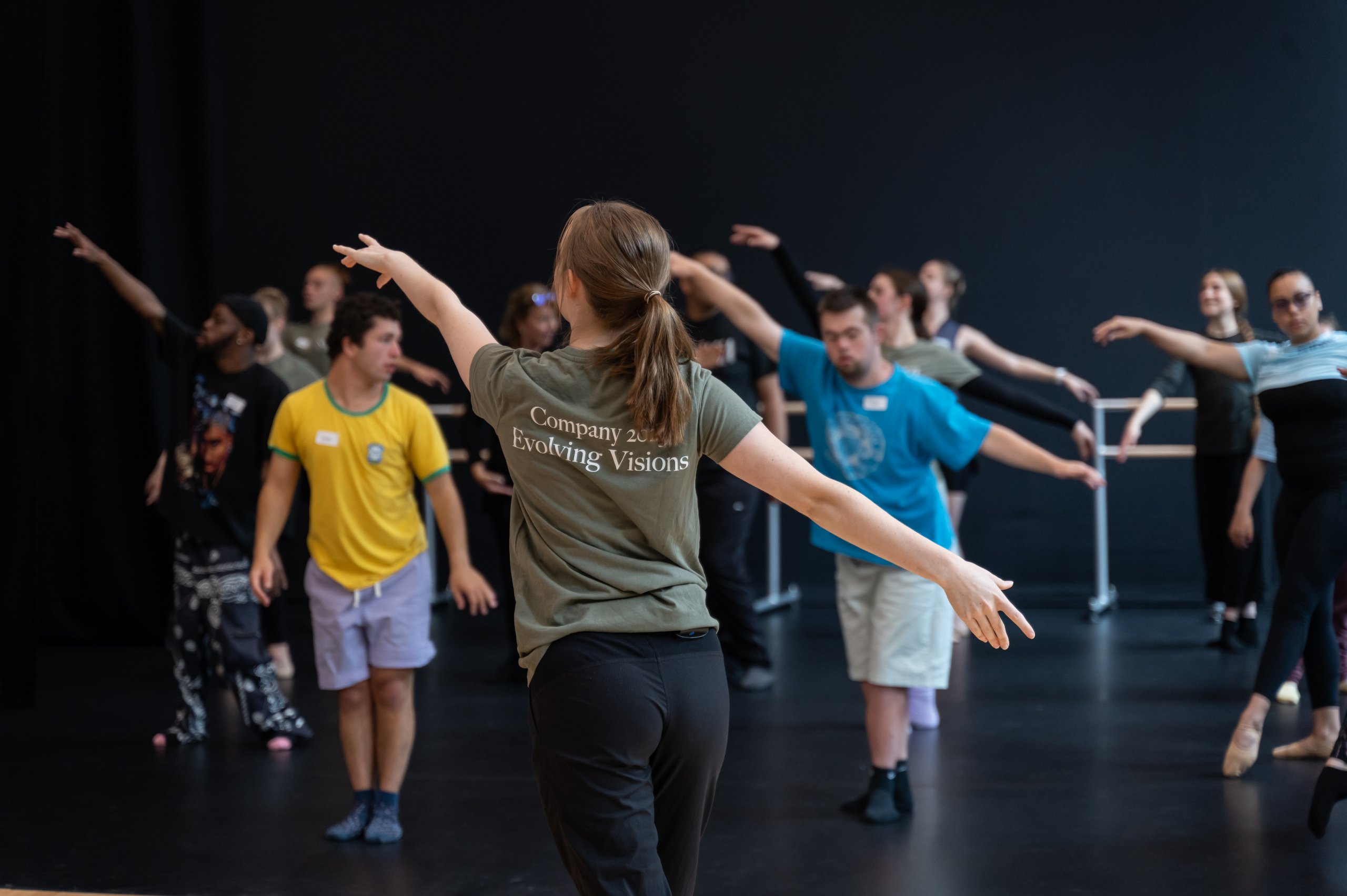 Dancers are reaching diagonally with the teacher demonstrating in front of them. 