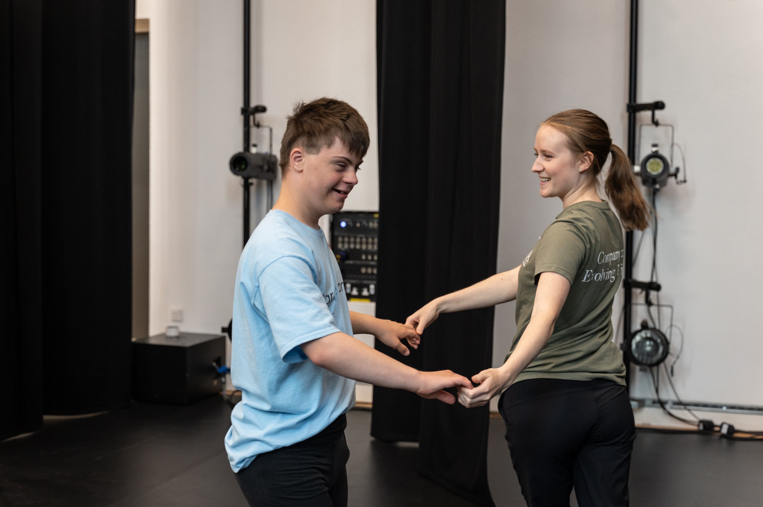 Two dancers holding both their hands facing each other and smiling. 