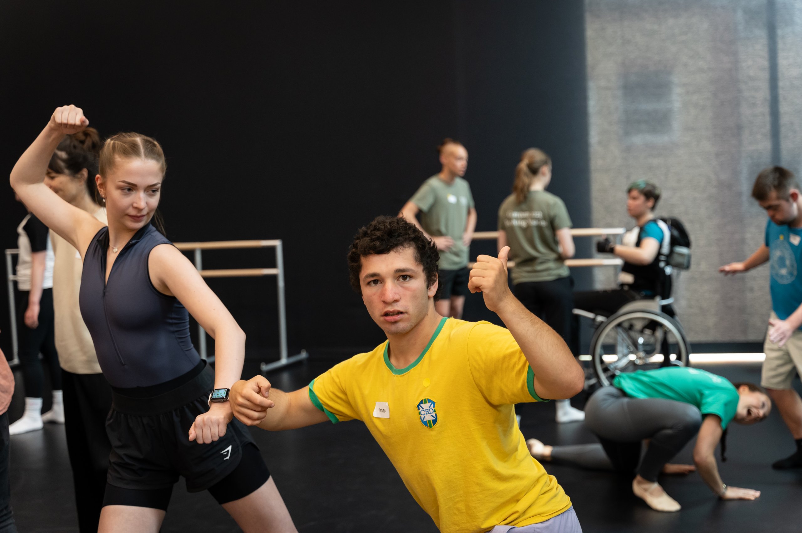 Many dancers with fists clenched motioning towards one another. 