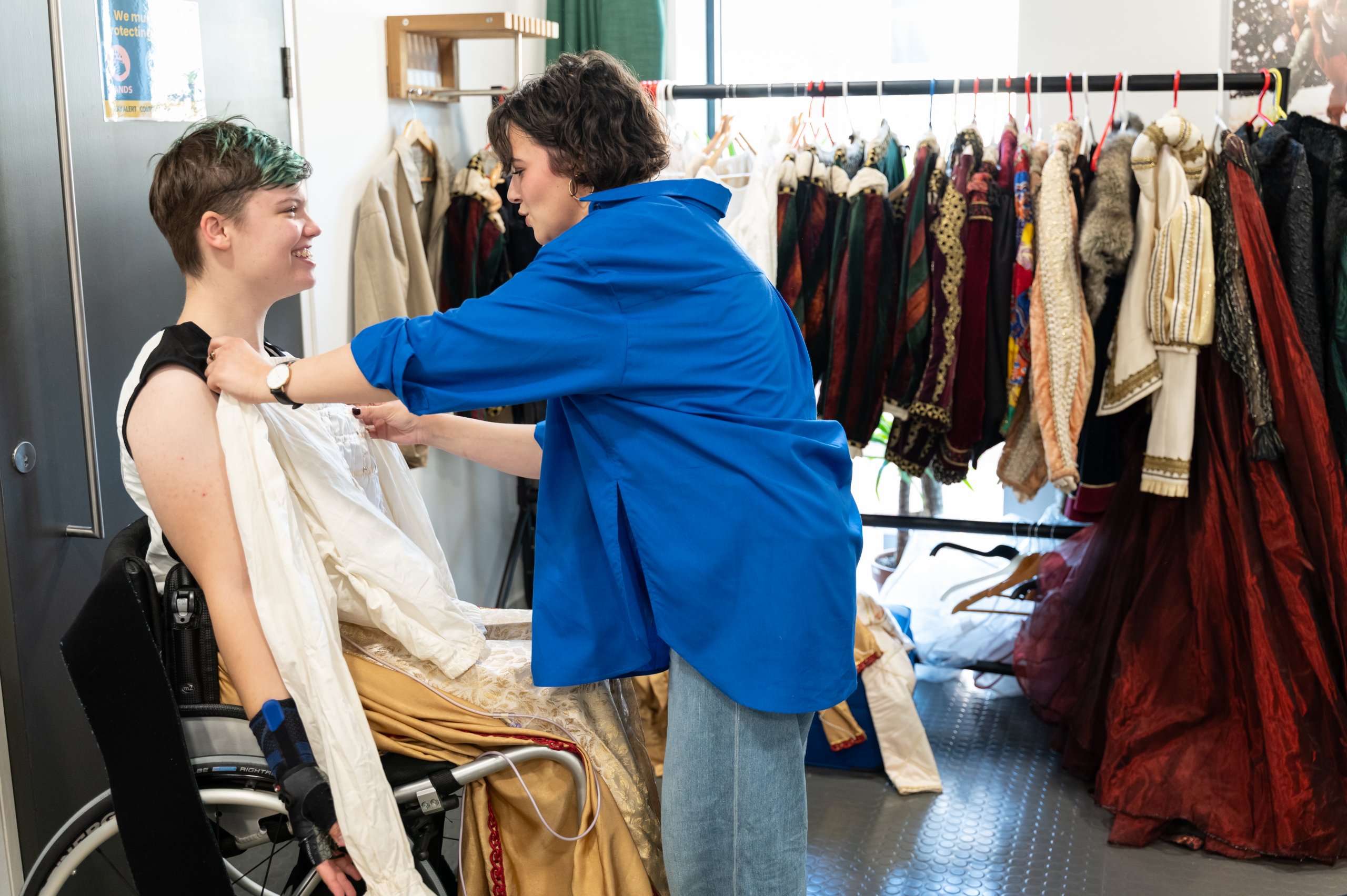 Person holding a white shirt up against a dancer in a wheelchair. 